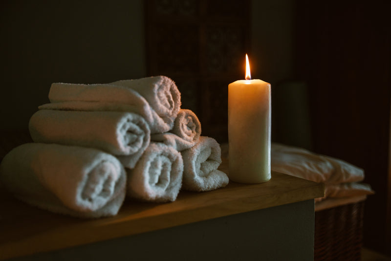 Candle lit spa setting with rolled towels and calming wellness ambiance for relaxation therapy